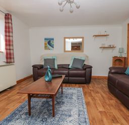 A living room with two brown leather sofas a wooden coffee table and a blue rug at Swallow Cottage in Bude