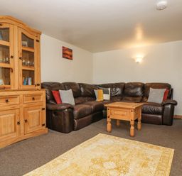 A living room with a brown leather sofa wooden cabinet and coffee table at The Wagon Linney in Bude