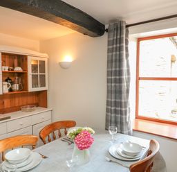 A dining area with a set table and a cabinet in the corner by a window at The Stable in Bude