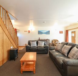 A living room with two black leather sofas a wooden coffee table and wooden staircase at The Dairy in Bude