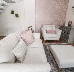 A living room with two light sofas a gray chest of drawers and floating shelves at Martingale in Torquay