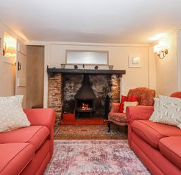 A living room with a fireplace and two sofas at Yew Tree Cottage in Stoke Fleming