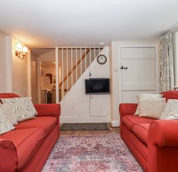 A living room with sofas and a clock at Yew Tree Cottage in Stoke Fleming