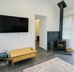 A living room with a television and a wood stove at 2 Mountain View Talwrn near Llangefni