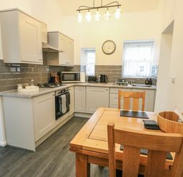 A kitchen with gray cabinets and a dining table at 2 Mountain View Talwrn near Llangefni