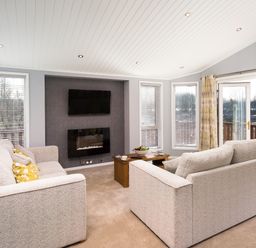 A living room with two sofas a wall mounted TV and a fireplace at Waternook Lodge in South Lakeland Leisure Village