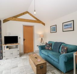 A living room with a blue sofa and wooden chest coffee table at The Cwtch in St Brides Major
