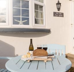 A small outdoor table with two chairs bread cheese wine bottle and two glasses at The Old Post Office in Bull Bay
