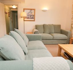 A living room with two green sofas a wooden coffee table and side tables a floor lamp and a framed picture on the wall at Sethera in Ambleside
