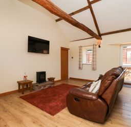 A living room with a sofa, rug, and television at Crabtree Cottage in Suffield near Scalby