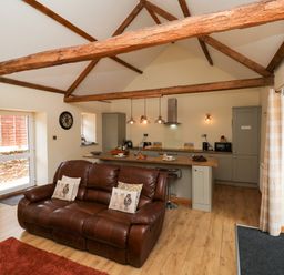 A living room with a sofa and kitchen area at Crabtree Cottage in Suffield near Scalby