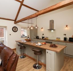 A kitchen with an island and bar stools at Crabtree Cottage in Suffield near Scalby