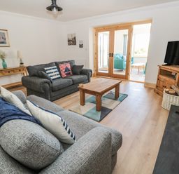 A living room with two sofas coffee table wooden cabinet and television at 24 Hauxley Links in Low Hauxley near Amble