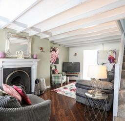 A living room with a fireplace sofas a television and stairs at Bryn Peris in Moelfre