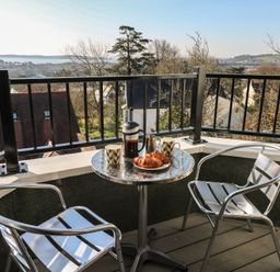 A balcony with a table, chairs, coffee maker, and croissants at Cambrie in Tenby