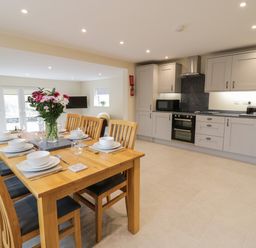 A kitchen and dining area with wooden dining table set for six and gray cabinets at Hen Dy Bryn Mawndy in Melin y Wig near Corwen