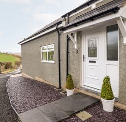 The exterior front entrance of a house with a white door and two potted plants at Hen Dy Bryn Mawndy Melin y Wig near Corwen