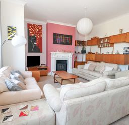 A living room with sofas a coffee table a fireplace and paintings at Victorian Town House in Weymouth