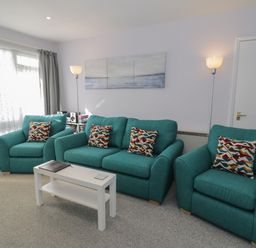 A living room with teal sofas and a white coffee table at Hafod-y-Gors in Fairbourne
