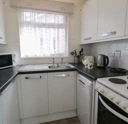 A kitchen with a microwave oven sink electric stove kettle and utensils at Hafod-y-Gors in Fairbourne