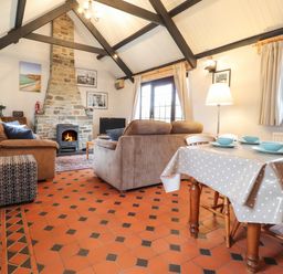 A living room with a stone fireplace a dining table with blue bowls and chairs at Bwthyn Alarch in Trefin St Davids Pembrokeshire