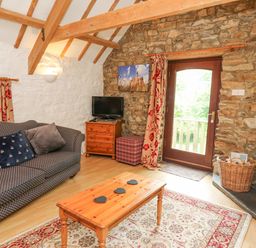 A living room with a sofa coffee table television and fireplace at The Granary in Newport Pembrokeshire