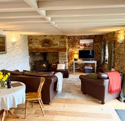 A living room with a sofa, dining table, and television at Stable Cottage in Newport, Pembrokeshire