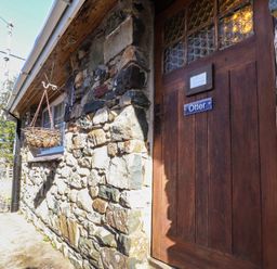 A stone exterior wall with a wooden door labeled Otter and a hanging basket at Otter Cottage in Dinas Cross