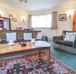 A living room with sofas coffee table bookshelf and window at Otter Cottage in Dinas Cross