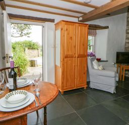 A living room with a dining table and wardrobe at West End Cottage in Newport, Pembrokeshire