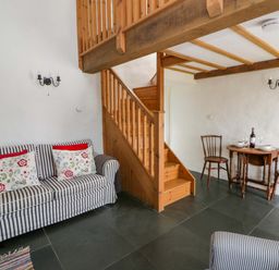 A living room with a sofa and dining area at West End Cottage in Newport, Pembrokeshire