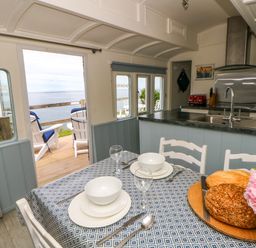 A kitchen with a dining table and chairs at Clifftop Carriage in Aberporth, Ceredigion