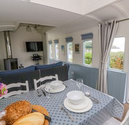 A dining room with a table set for meals at Clifftop Carriage Aberporth, Ceredigion