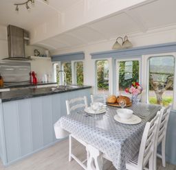 A kitchen with a table set for dining at Clifftop Carriage in Aberporth, Ceredigion
