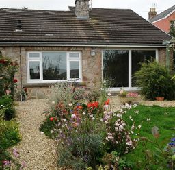 A stone house with a pebble pathway and garden with flowers and greenery at Gellifor in St Dogmaels Pembrokeshire