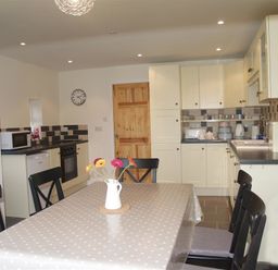 A kitchen with a dining table covered with a polka dot tablecloth and a vase with flowers at Gellifor in St Dogmaels Pembrokeshire
