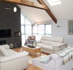 A living room with sofas and a wooden coffee table near a stone fireplace at Seabrook Broad Haven Pembrokeshire