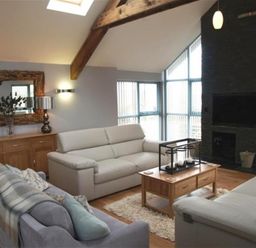 A living room with sofas a wooden coffee table and fireplace at Seabrook in Broad Haven Pembrokeshire