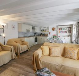 A living room with a sofa and kitchen area at End Cottage in Newport, Pembrokeshire