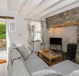 A living room with a sofa, table, television, and lamp at Middle Cottage in Newport, Pembrokeshire