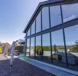 Outdoor view of a house with large windows and a garden at The Willows in Newport, Pembrokeshire