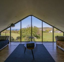 A living room with large windows showing the view at The Willows in Newport, Pembrokeshire