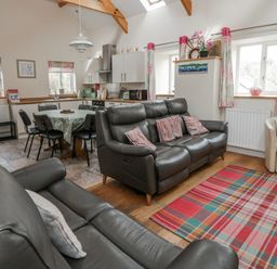 A living room with a sofa and dining area at Y Felin in Cardigan, Ceredigion