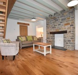 A living room with wooden floor sofa armchair coffee table and stone fireplace at The Old Farmhouse Kitchen in St Davids Pembrokeshire