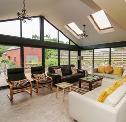 A living room with sofas chairs and glass walls at Nevern House in Newport Pembrokeshire
