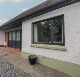 The exterior of a house with a window and sliding door a black flower pot on the ground at Greenfields in St Davids Pembrokeshire