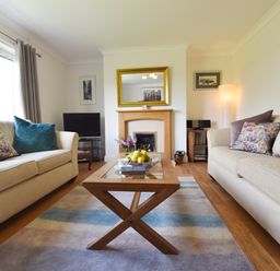 A living room with two beige sofas a wooden coffee table and a fireplace at Greenfields in St Davids Pembrokeshire