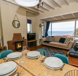 A living room with a sofa and fireplace at Delyn Aur in Tresaith, Ceredigion