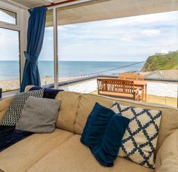 A living room with a view of the sea and outdoor seating at Delyn Aur, Tresaith, Ceredigion