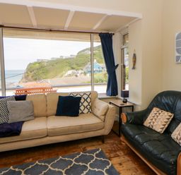 A living room with sofas and a view of the coast at Delyn Aur Tresaith, Ceredigion